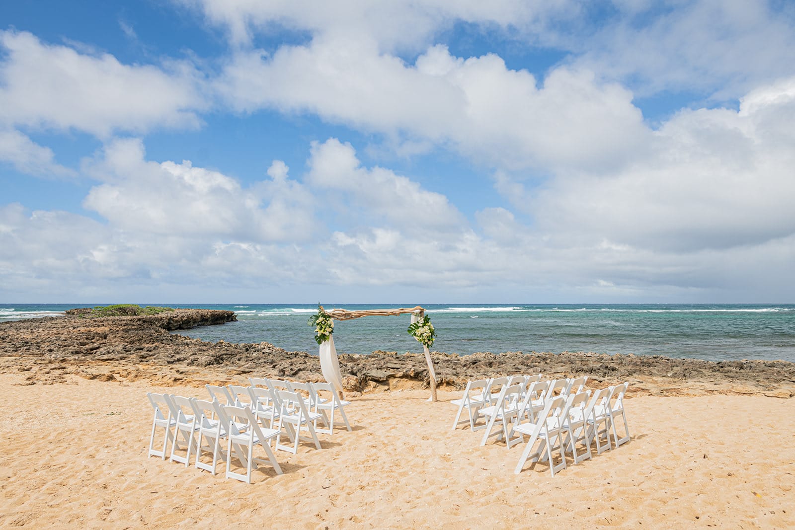 A beach ceremony set up for guests on the North Shore of Oahu, the ocean behind