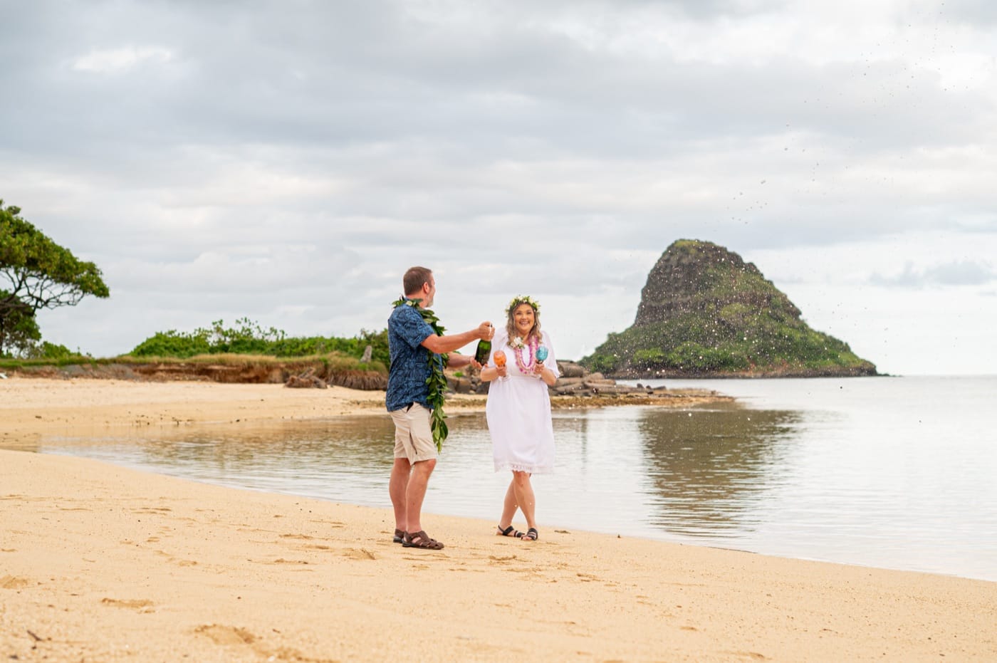 A couple on the sand at Kualoa with Mokoli'i island behind them